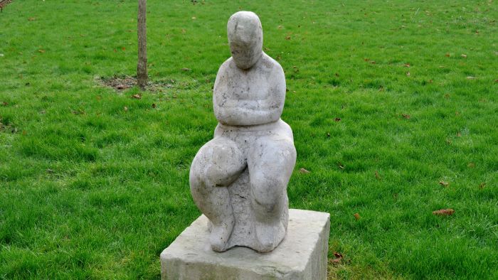 Zittende vrouwenfiguur met gekruiste armen